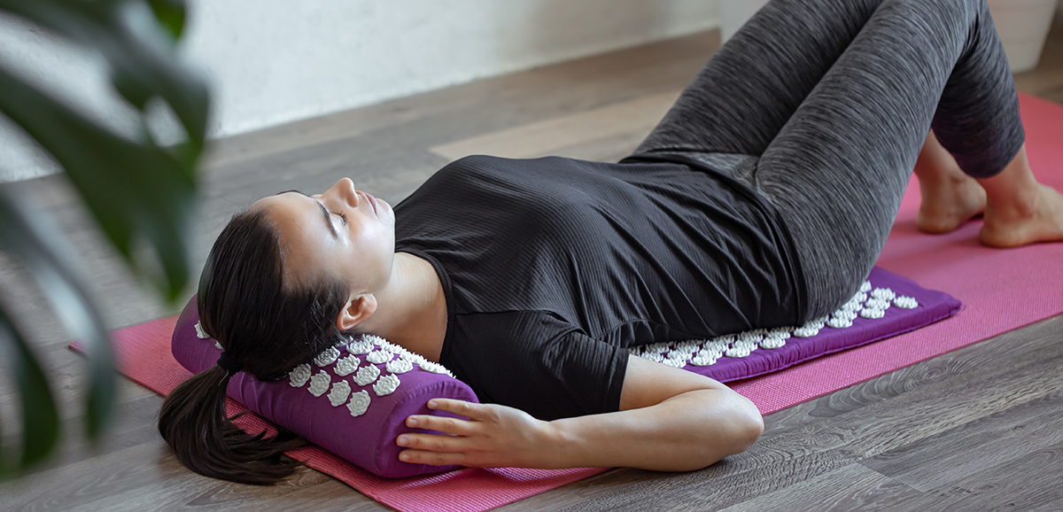 Young woman on acupressure mat in home acupuncture massage.